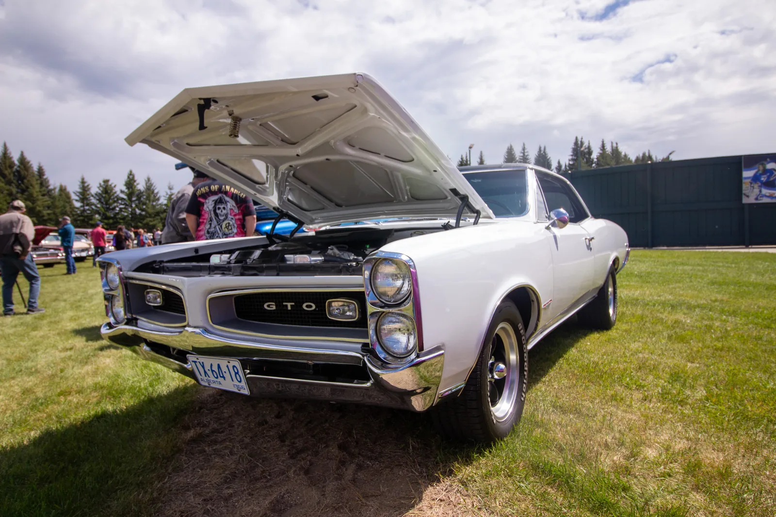 A white GTO with its hood up at the Clymont car show