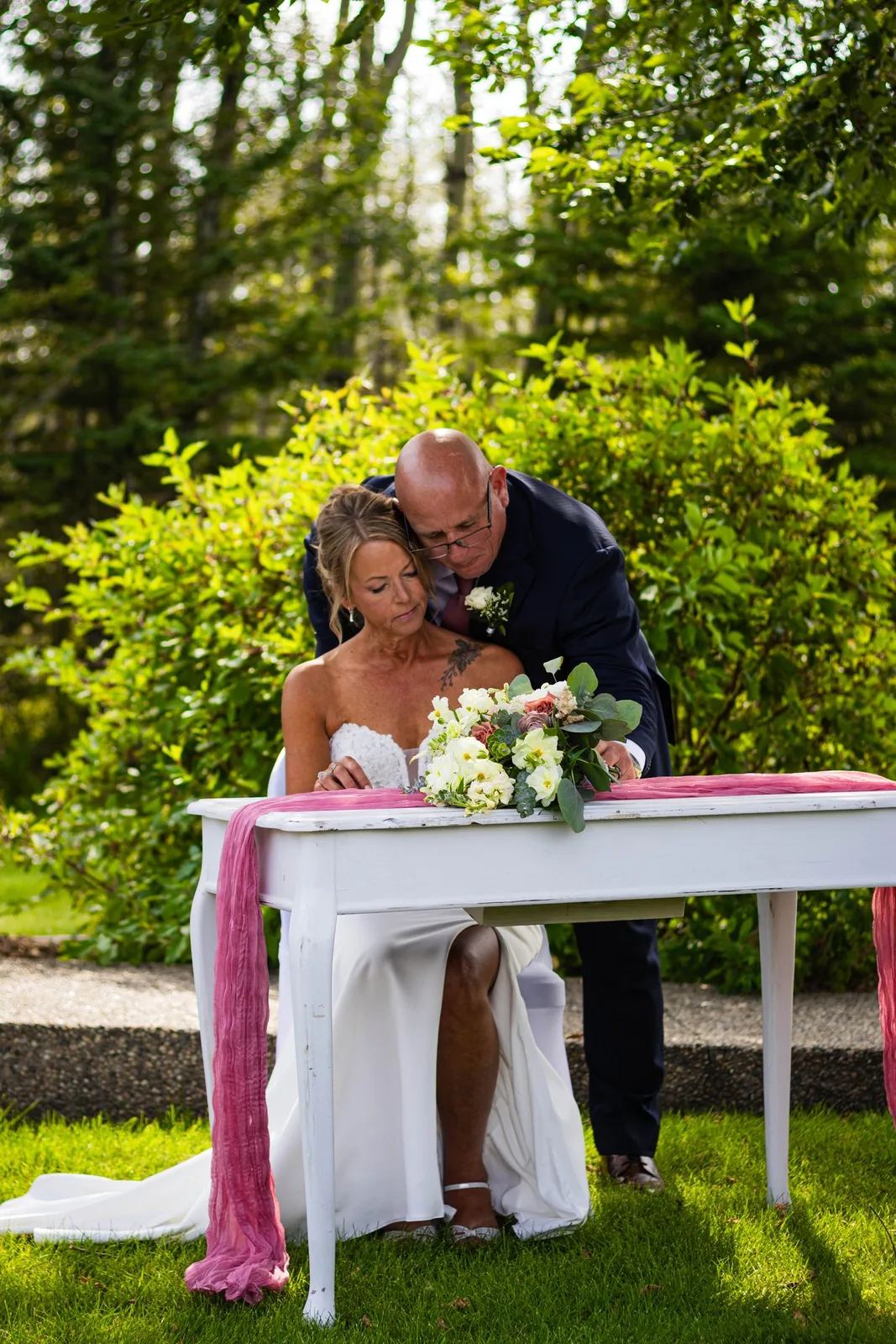 A couple signing their marriage papers at an outdoor table